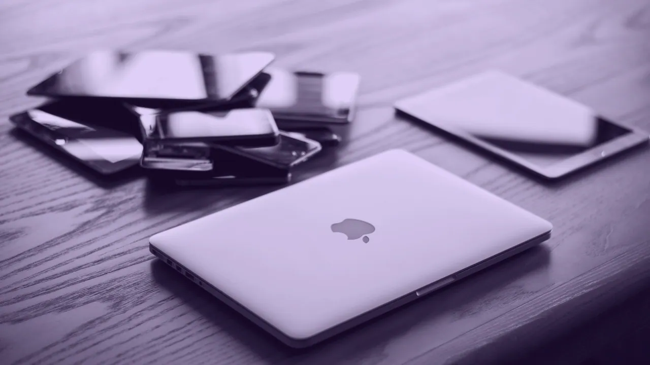 A laptop, a phone and a tablet together on one table.