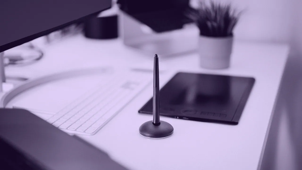 A tablet on a desk beside a stylus.