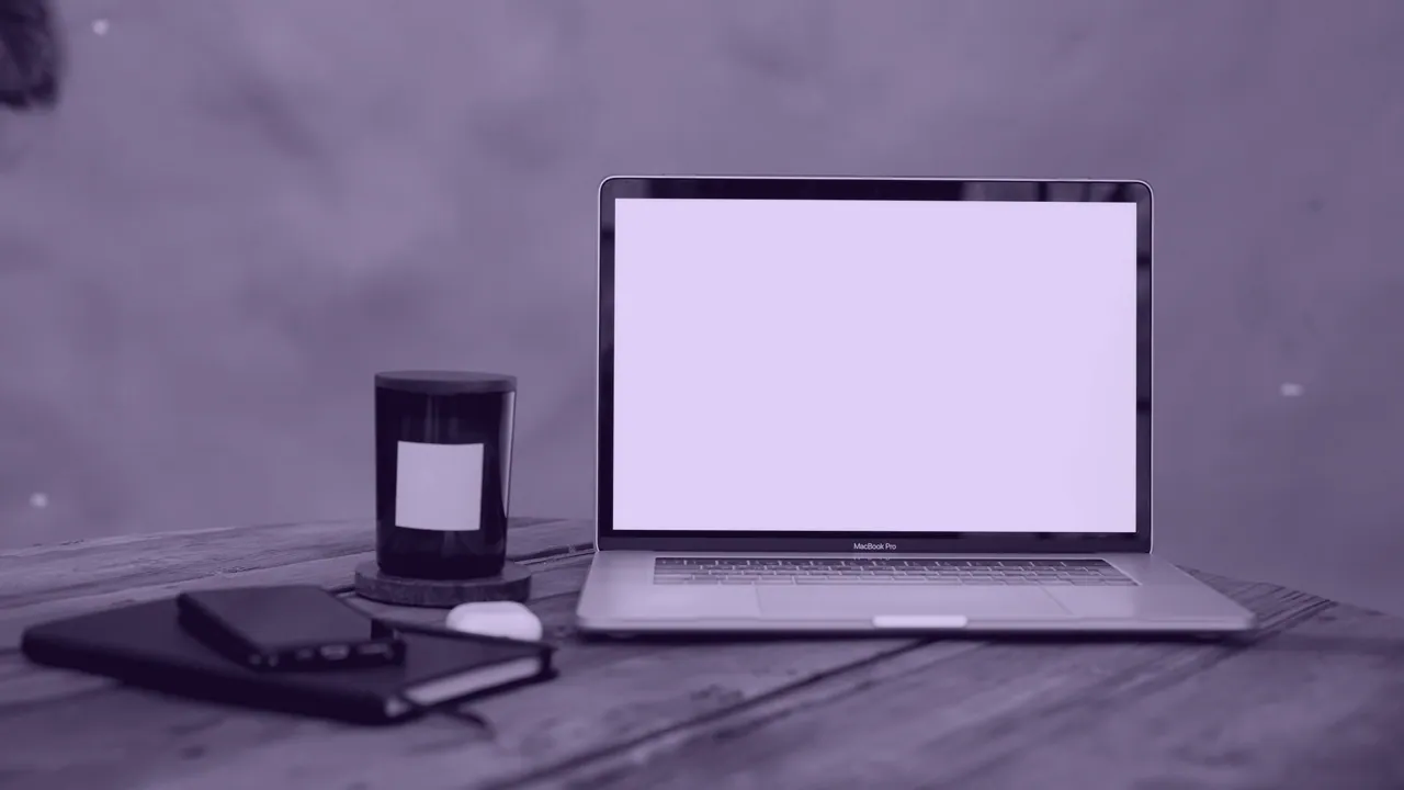 An open laptop on a wooden table with the screen lit.