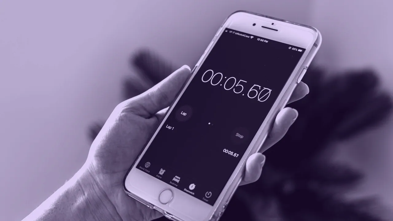 A phone held in one hand, showing the time on its lock screen.