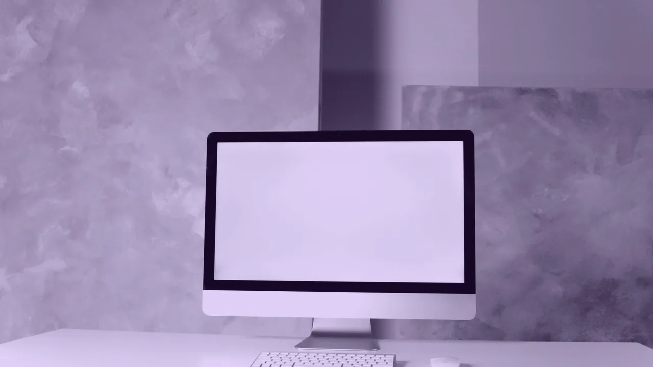 An all-in-one Apple desktop computer on a pale desk.