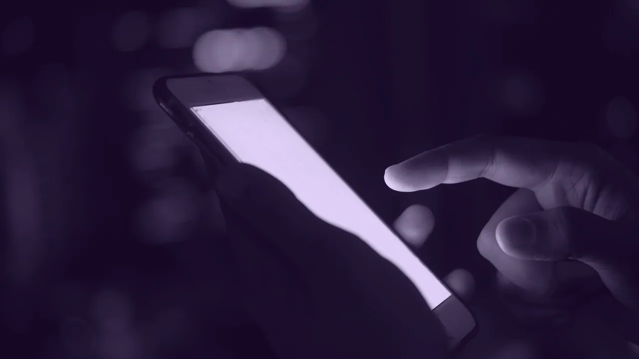 A phone screen glowing in someone hand at night.