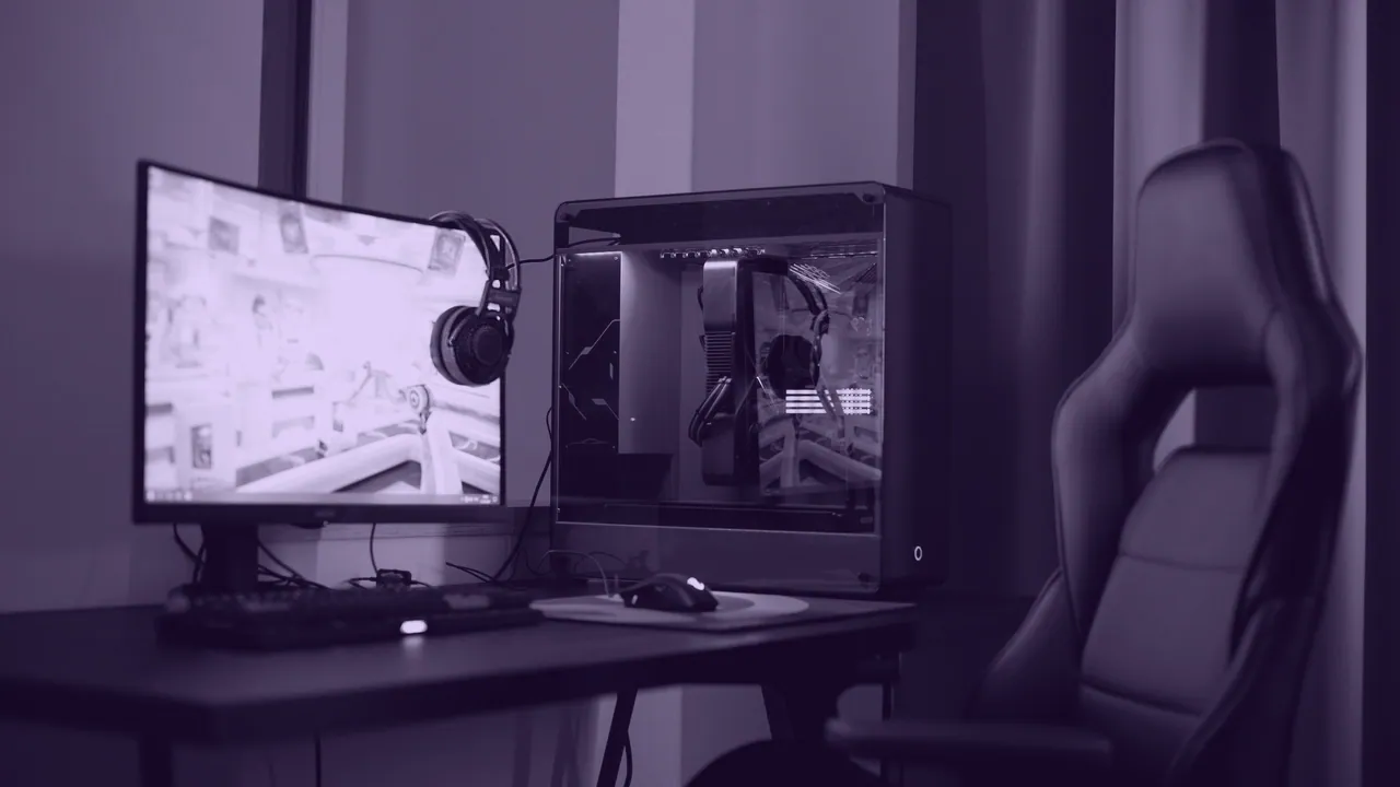 A gaming desk: widescreen monitor, keyboard and headset.