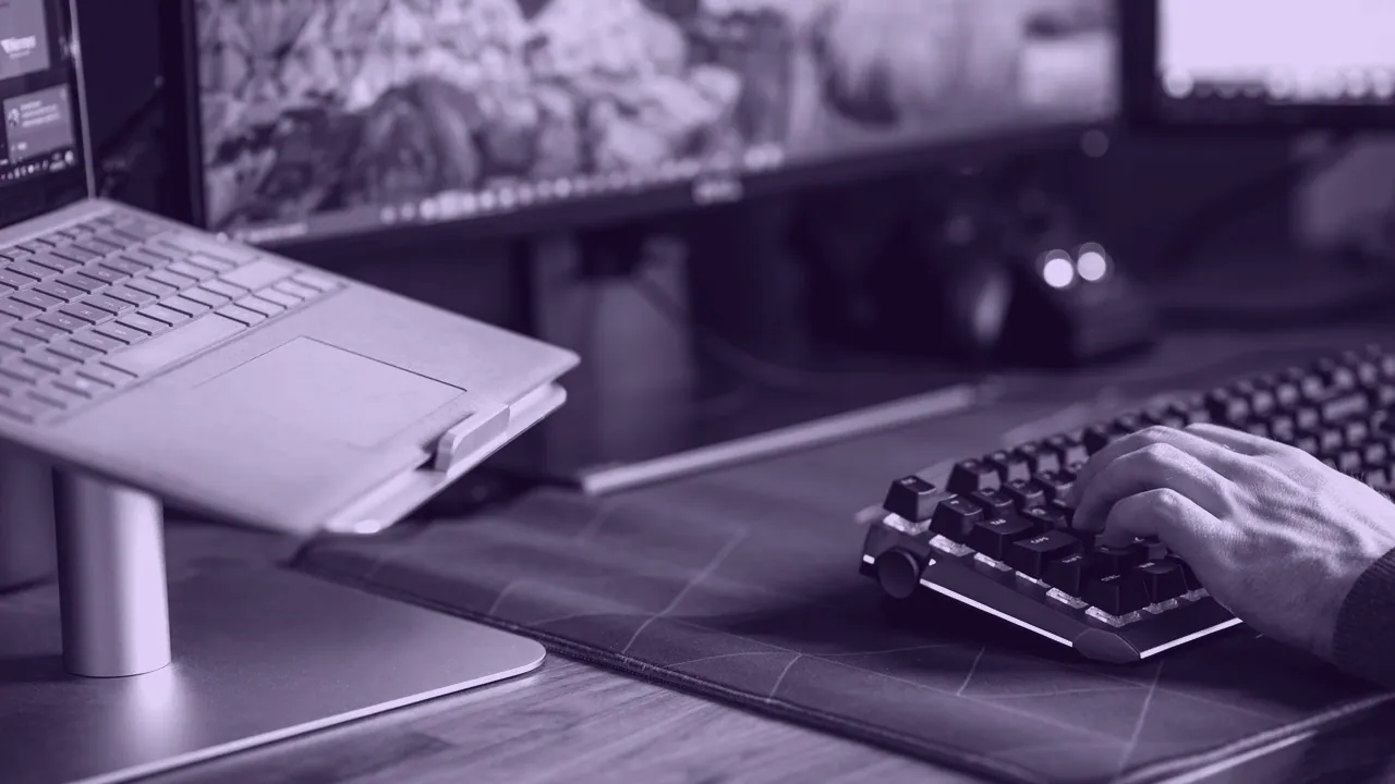 A black desktop monitor with a mechanical keyboard.